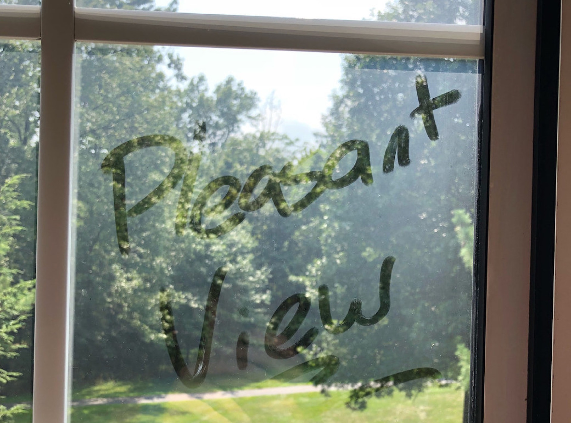 Technician cleaning residential windows on a two-story home